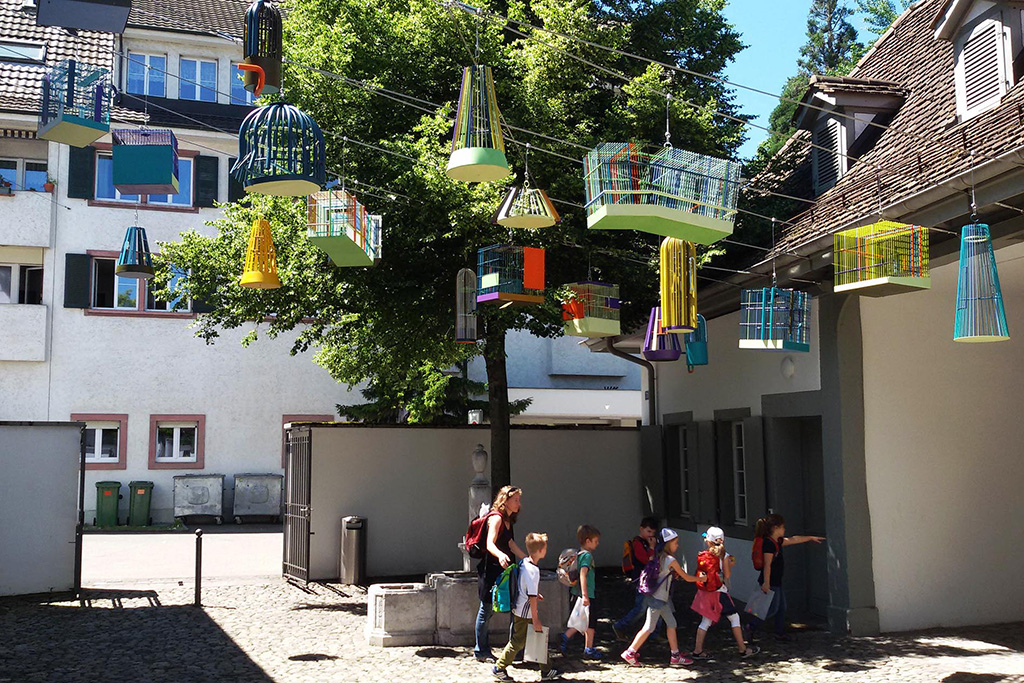 Children walking under cages designed by Tobias Rehberger at Riehen in the outskirts of Basel