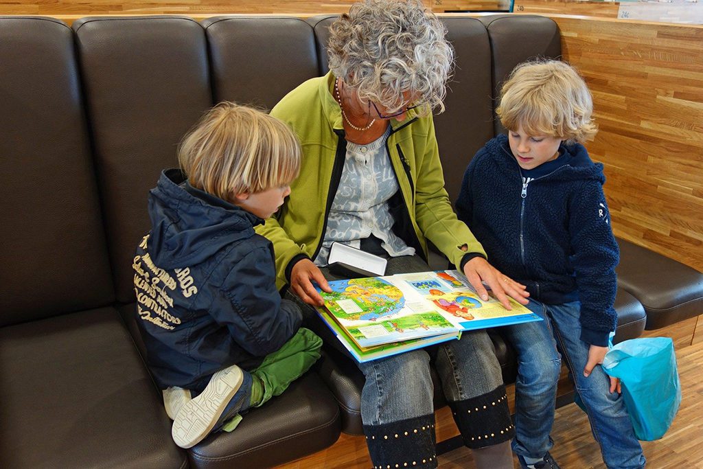 Lady showing a book to two boys