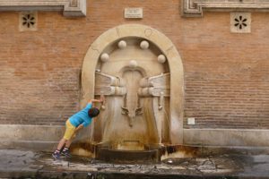 Boy drinking from the Fountain of Books in Rome