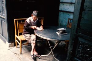 Old gentleman writing in Hoi An