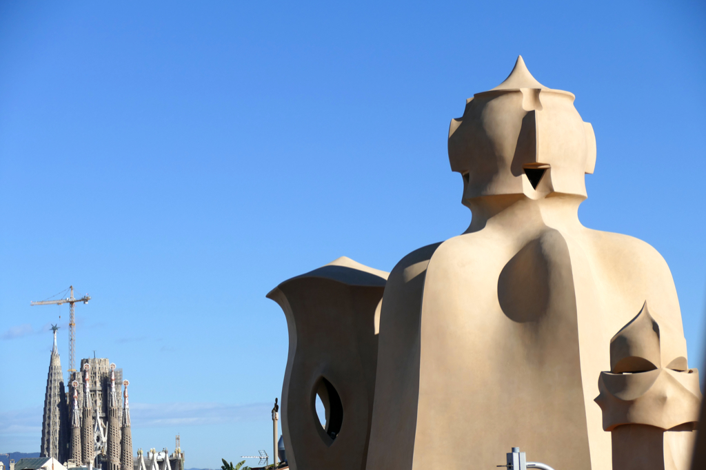 Gaudi's two most iconic works in together: The chimneys of the Casa Mila with the Sagrada Familia in the backdrop. Gaudi Barcelona Guide Modernism