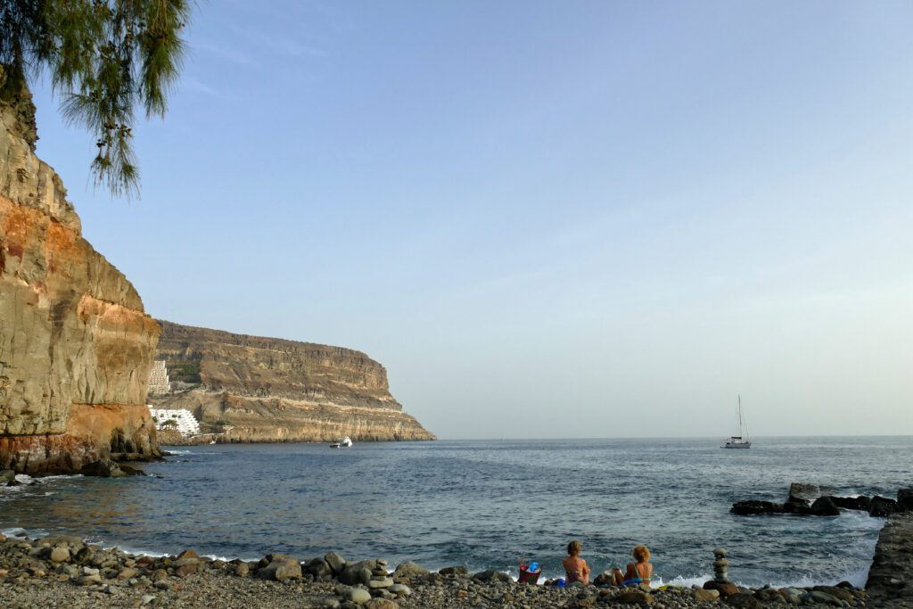 Women sitting on a beach at Puerto de Mogan.