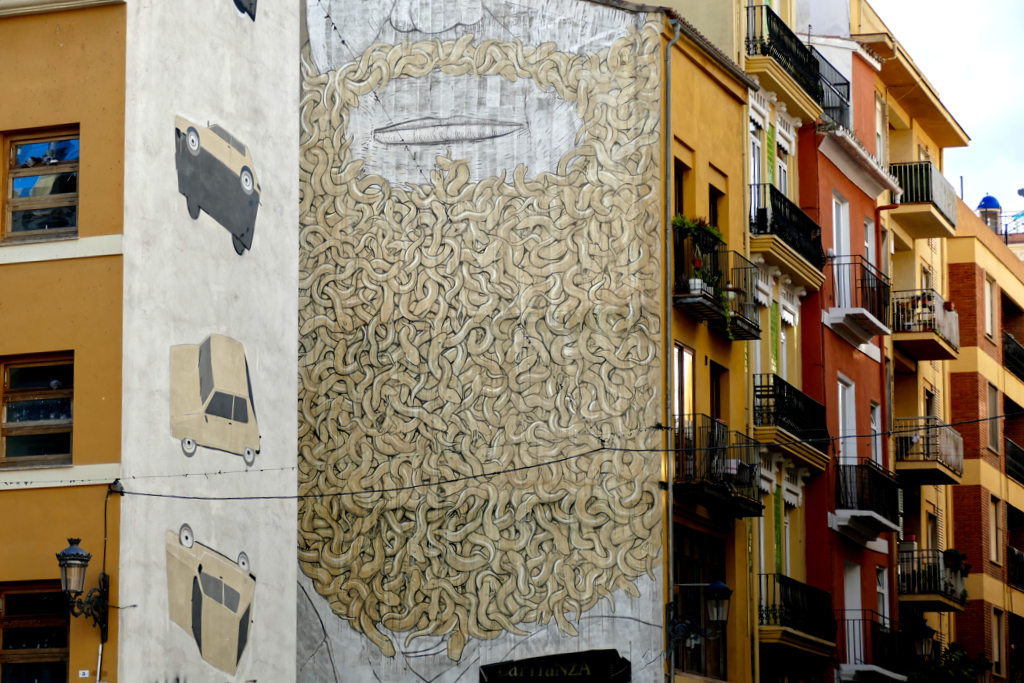 Tumbling cars by Escif to the left, Moses with a beard made from snakes by the Italian artist Blu to the right.