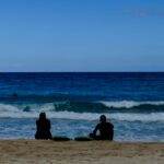 Two surfers sitting on the beach of Corralejo in Fuerteventura