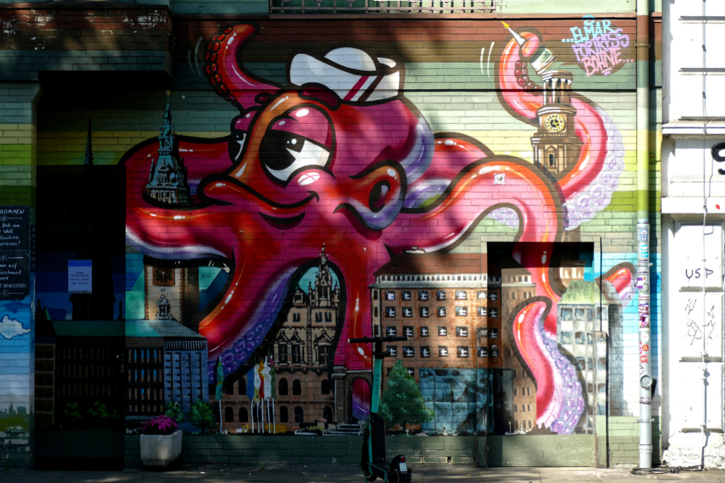 Mural of a A cute octopus with a sailor hat hugging the whole city of Hamburg. The artist behind it is Elmar Lause.