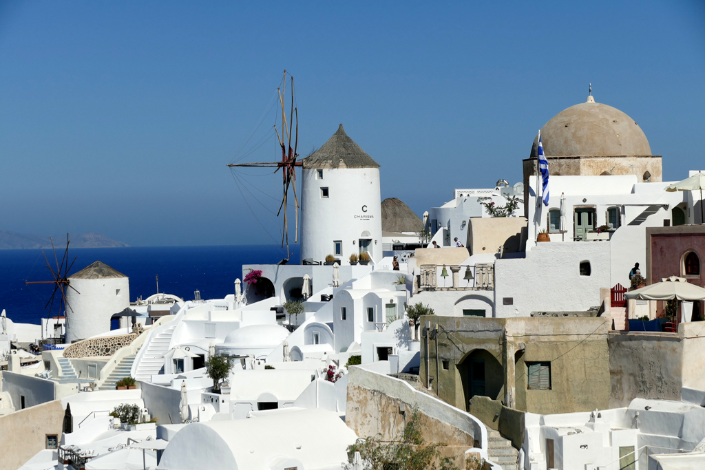Windmills of Oia with the dome of the Holy Orthodox Church of Saint Ekaterini to the right.