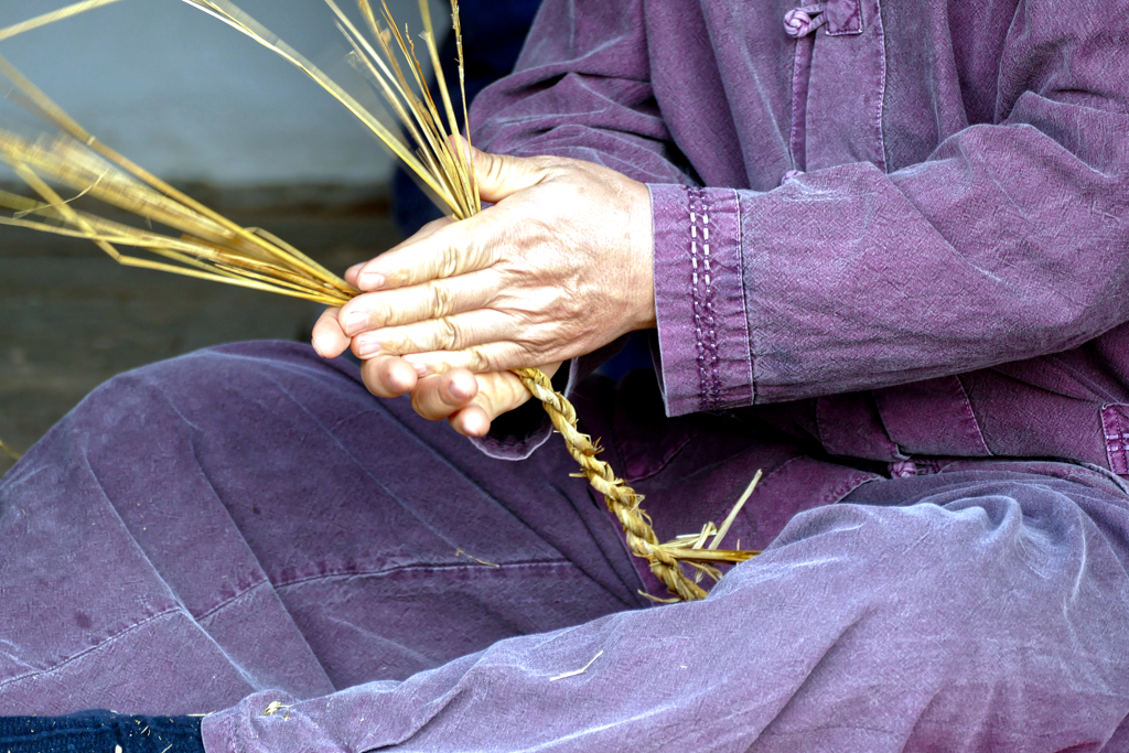 Man making souvenirs from rice stalks.