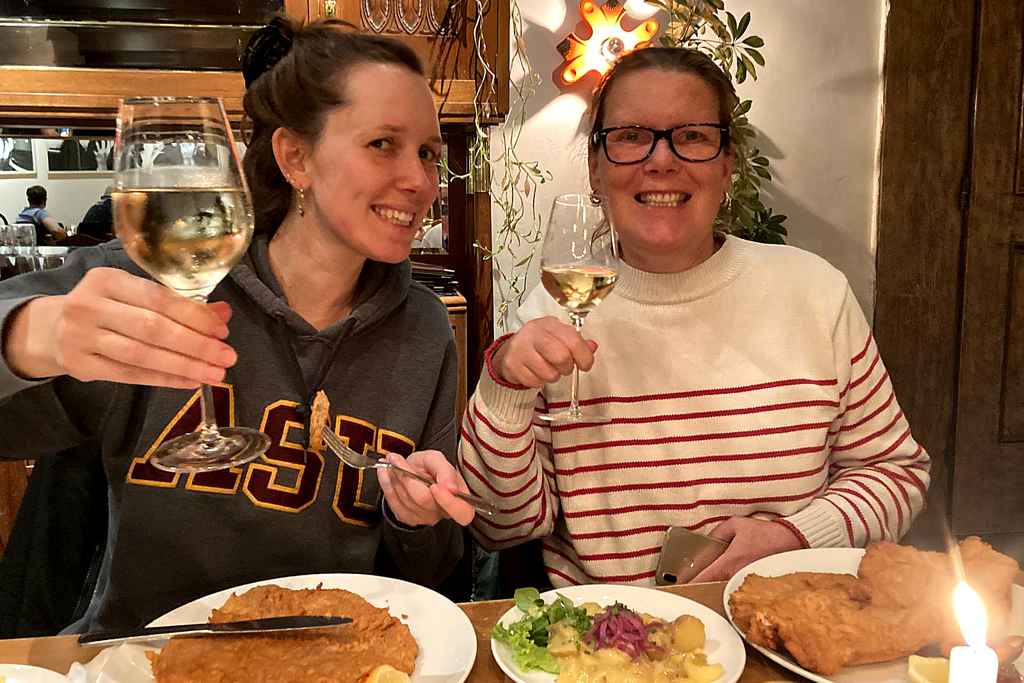 Women eating Schnitzel and drinking wine in Vienna.