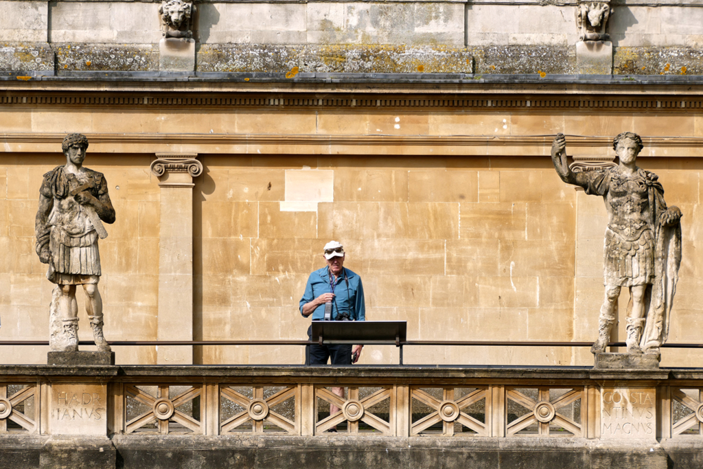 Man reading a sign at the Roman Bath in Bath, the most beautiful city in Britain.