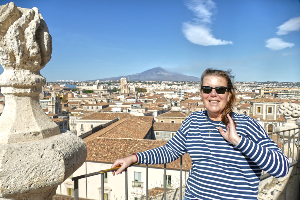 Renata Green standing on the balcony of the Chiesa della Badia di Sant'Agata church with the Etna in the backdrop.