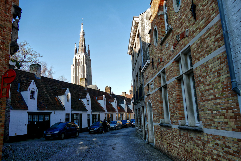 The historic Groeninge alley with the striking Gothic church tower of the Church Onze-Lieve-Vrouwekerk in the background.