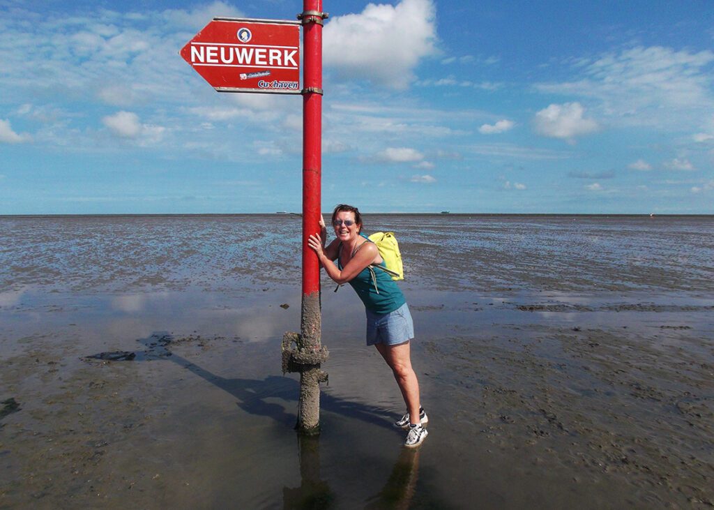 Renata Green with a sign pointing towards Neuwerk when walking on water from Cuxhaven